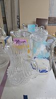 Clear Hobnail and Corelle decorated pitchers and punch bowl on table.