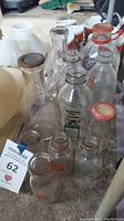 Photo showing assorted glass milk bottles from front angle with visible logos and bottle shapes.