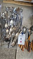 Mixed vintage flatware piled together showing spoons, forks, and knives, some silver plated, tarnished and in need of cleaning.