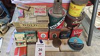 Overview of various vintage tobacco tins and cigar boxes arranged on table surface, showcasing brands and condition.