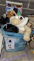 Clear bin with TY Beanie Babies plush on top and some magazines or papers to the side