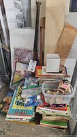 Photo showing wooden baseball bats, assorted paperback books, and various small items in a box including a Peanuts Lucy figure head