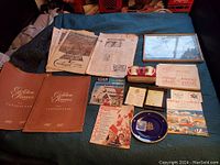 Full view of the 1967 Centennial lot showing framed Expo 67 aerial photo, tourist kits, Golden Leaves books, plate, medallions, Fire King mugs, and various papers