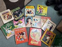 Photo of 12 assorted children's books and comic books including Bugs Bunny, Popeye, The Strawberry Fairy, The Animals of Farmer Jones, The Night Before Christmas, and others.
