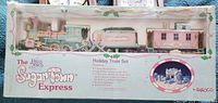 Full boxed view of the Precious Moments Sugar Town Express Holiday Train Set with all cars and track shown in packaging.