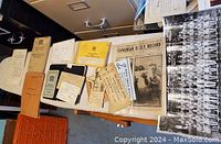 Lot of assorted WWI and WWII papers, coupons, newspapers, documentation, and photographs spread out on a table, showing multiple types of documents and a large black and white group photo.