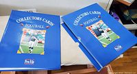 Two blue ProFile "Collectors Cards Football" binders side by side on table, one partially inside its sleeve case.