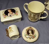 Four commemorative china items including lidded box, two-handled mug, gold lion-handled mug, and pomander showing front and top details