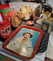 Group image showing seven tins and trays all featuring Queen Elizabeth II portraits with varying designs and colors.