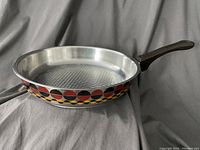 Side angle showing entire skillet including interior raised dot pattern and colorful geometric pattern on outside.