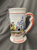 Front side of Disney mug showing Sleeping Beauty Castle scene and detailed Disneyland park illustration with characters and landscaping.