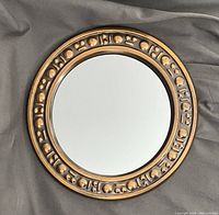 Front view of the round mid-century wall mirror showing the decorative copper finish frame and reflective glass center.