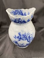Front angled view of small antique porcelain vase showing blue floral design, scalloped rim, and bulbous shape.