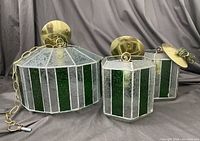 Photo showing full set of three stained glass hanging lamps including one large and two smaller units arranged on fabric background.