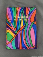 Front view of vintage fabric covered telephone and address book with multicolor abstract design and gold lettering "Telephone & Address".
