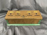 Front top view of the vintage coin box showing four coin slots on top and areas for labels with a central key lock (key missing).