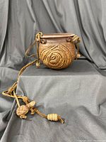 Pottery hanging planter with visible spiral textured design and leather hanging straps with decorative knots and turtle charm.