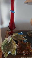 Group shot showing tall red vase behind two swirl dishes and amber ashtray