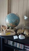 Photo showing vintage globe, seashell bookends, wounded Gaul statue, Hope Rock, and handpainted rock on shelf