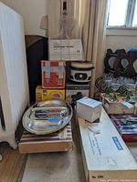 Photo showing boxed hamburger broiler and various kitchen appliances and trays stacked near window.