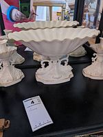 View of the Lenox Aquarius pedestal compote bowl and two candle holders arranged on a black surface with mirror behind.