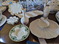 Photo showing multiple Lenox porcelain pieces including shell-shaped chip and dish plate, vases, trinket dish, lotus-shaped candle holders, and condiment plate with floral pattern.