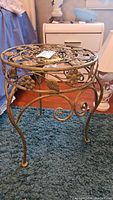 Side view of the metal accent table showing curved legs and leaf/flower metal accents.