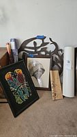 Photo showing signed 24x24 metal sculpture wall art with bird and female figure cutouts, framed photo of woman with hat, framed colorful parrot artwork, and rolled posters.