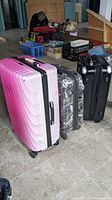 Three assorted hard shell suitcases standing upright in a row, showing different colors and designs.