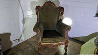 Front view of classic Queen Anne style chair showing carved wood frame and green velvet upholstery.