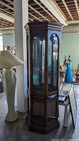 Full view of the curio cabinet from the front-left angle showing the glass shelves inside and wood finish