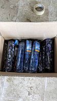 Box containing 12 new fold-up umbrellas in original packaging, showing a mix of purple floral and blue plaid patterns.