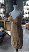 Front view of the beige silk dress with spaghetti straps and ruching detail on the bust and skirt areas.