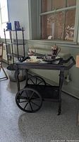 Front and side view of dark wood tea trolley with removable glass tray intact, showing large spoked wheels and curved legs.