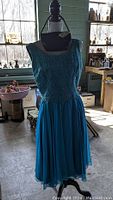Front view of aqua vintage dress on mannequin showing lace bodice and flowing chiffon skirt.
