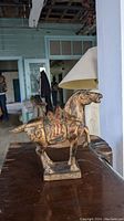 Photo of wooden horse sculpture painted in bronze, showing detailed horse figure on rectangular base.