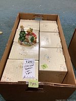 View of box containing seven Cherished Teddies figurine boxes with one figurine outside the box on top showing crafting holiday bear and Christmas tree.