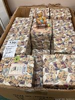 Box containing approximately twenty Cherished Teddies figurines in original boxes, each decorated with collage teddy bear images and Cherished Teddies branding.