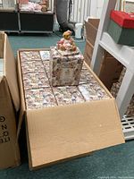 Box with multiple individual Cherished Teddies figurine boxes inside and one figurine displayed on top.