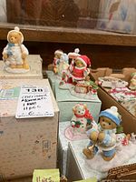 Overview of multiple Cherished Teddies figurines displayed on original boxes, showing varied styles and holiday themes.