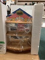 Full view of the wooden Cherished Teddies display case with three shelves, wrapped in plastic and secured by foam on the sides.