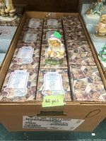 Box containing 32 pieces of Cherished Teddies figurines in original packaging with price tags and labels visible.