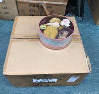 Eight Cherished Teddies tins stacked on a cardboard box showing size and packaging