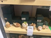 Shelf display of approximately 7 small Harmony Kingdom animal figures in front of stacked original green boxes with gold logo.