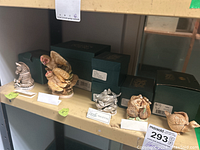 Shelf showing six Harmony Kingdom figurines with their original green boxes behind each figure.