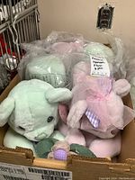 Photo showing assortment of six plush bears in pastel colors inside a box, some bears are individually wrapped in plastic bags.