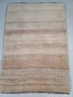 Full view of the Persian Gabbeh wool rug with natural color variations in beige and light brown stripes.