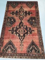 Full view of Persian Hamedan wool rug with central medallion and geometric motifs on reddish background with darker accents.