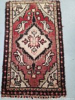Top view of hand-knotted Persian rug from Hamedan showing central diamond medallion with bird motifs in red, cream, and black colors.