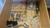 Full drawer view showing assortment of costume jewelry including beaded necklaces, earrings and bracelets arranged in clear organizer and on surface